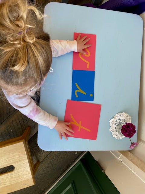 Child's hands on colorful letter cards on a light blue table
