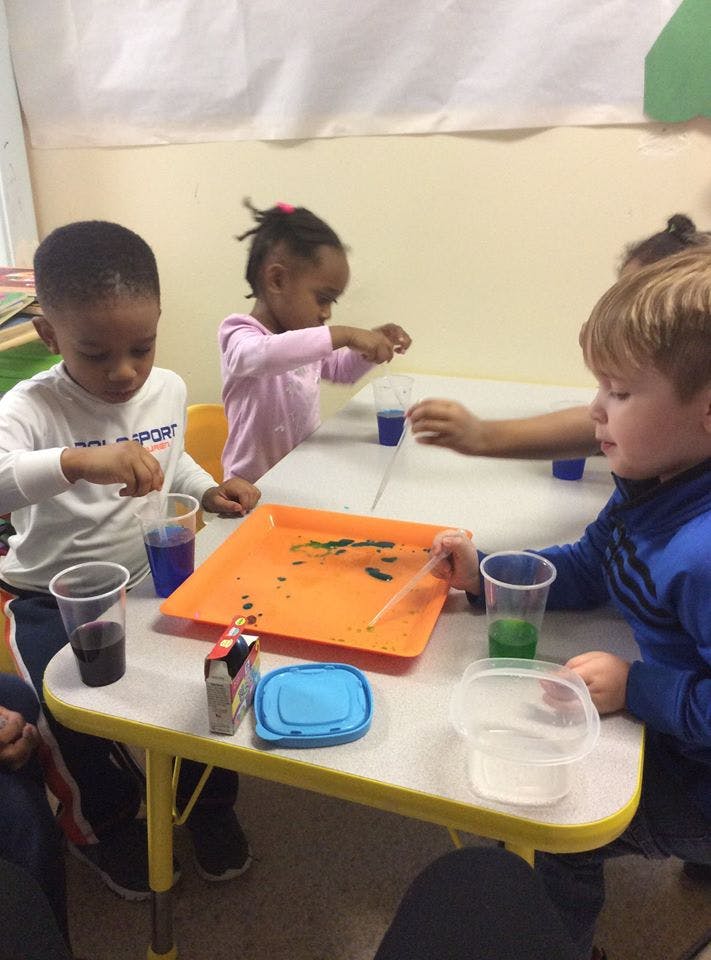 Children at a table with cups and an orange tray