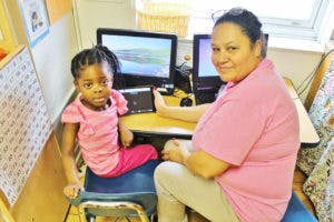 Adult and child sitting at a computer desk