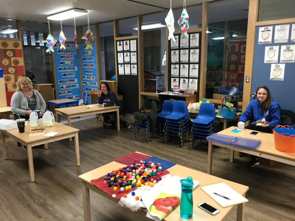 Three people sitting at tables in a room with craft supplies