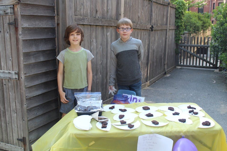 Two children standing behind a table with plates of food