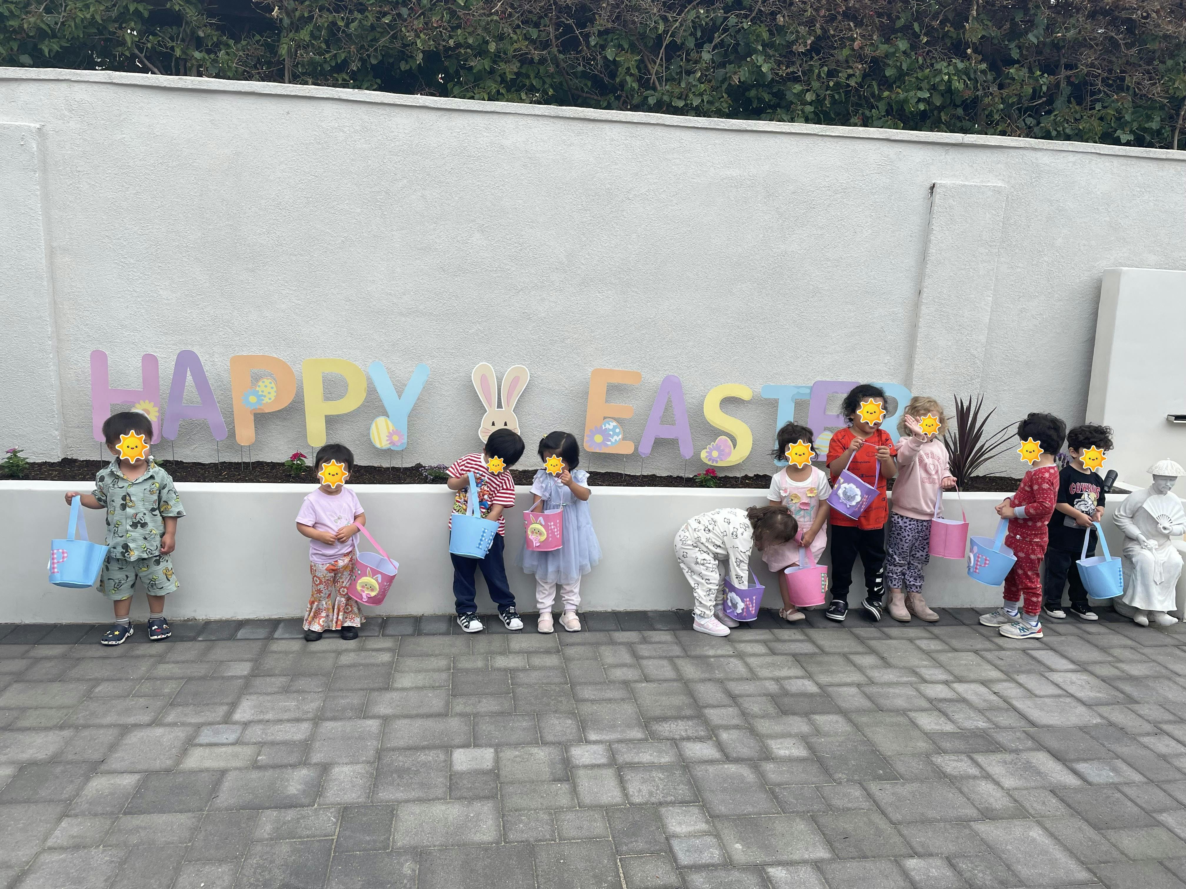 Children with buckets in front of "Happy Easter" sign