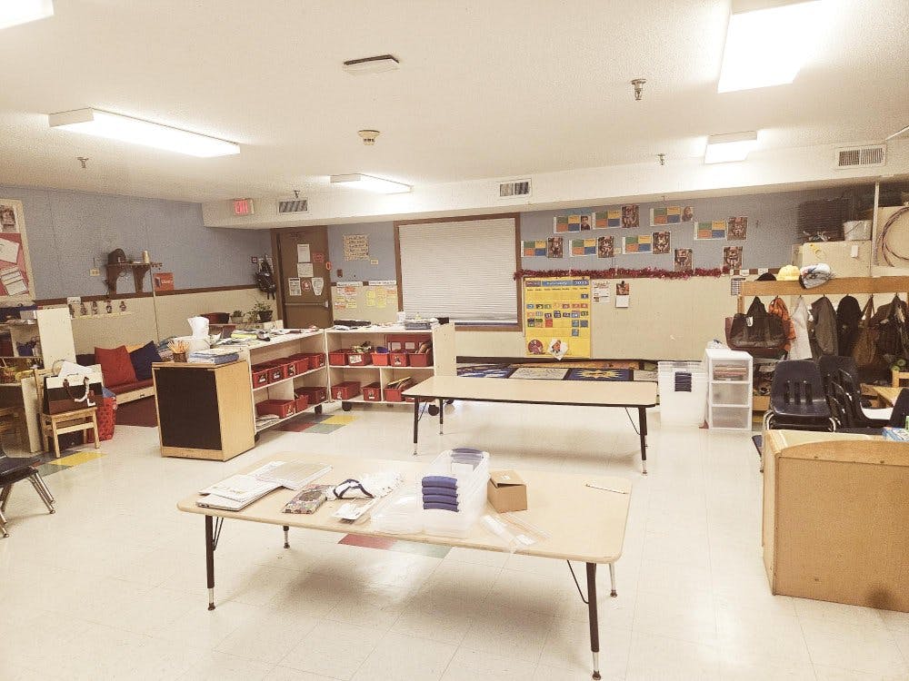 Classroom with tables, chairs, shelving units, and decorations on walls