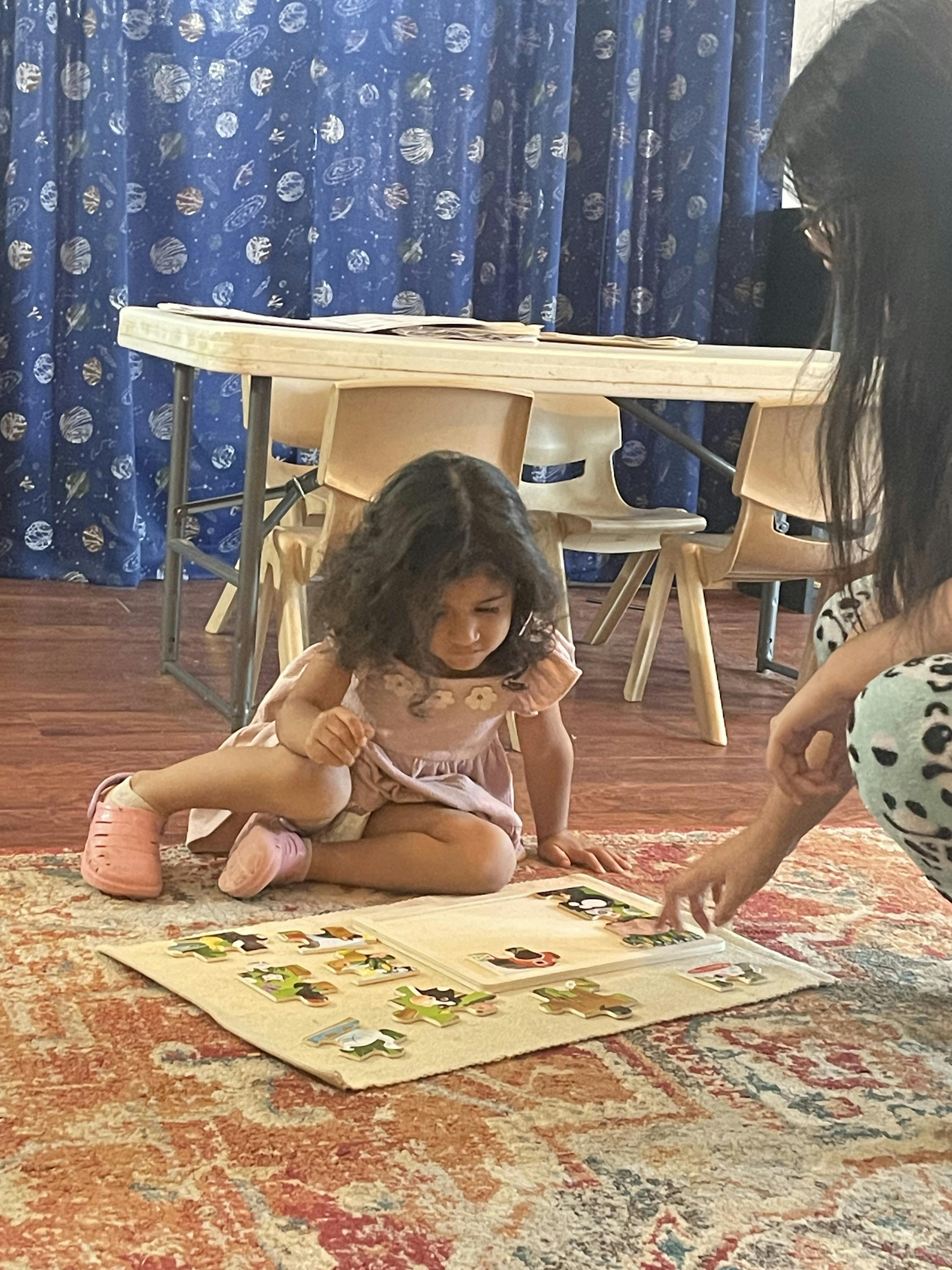Child and person on floor playing with a puzzle