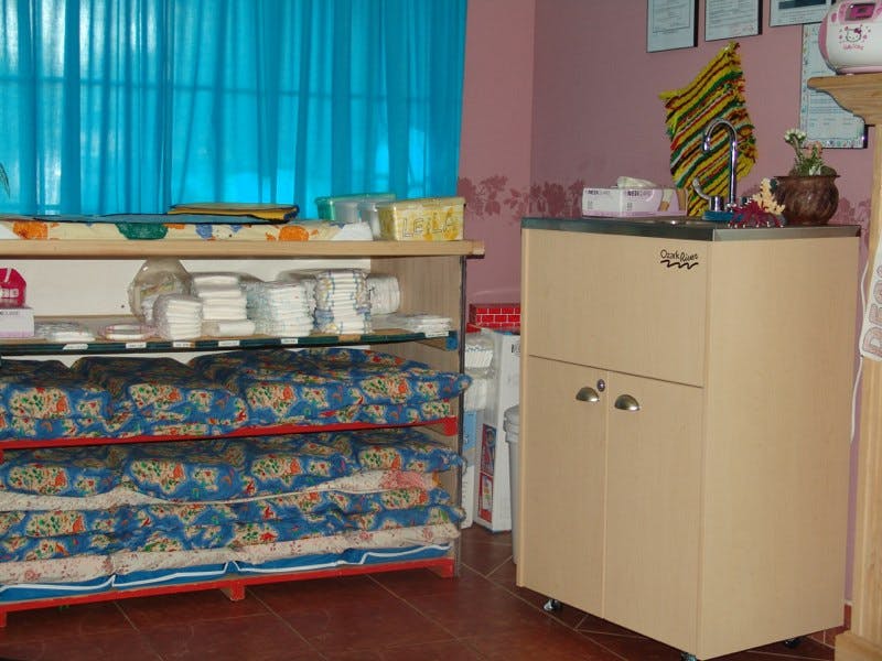 Shelving unit with stacked bedding and dishes next to a cabinet with a sink