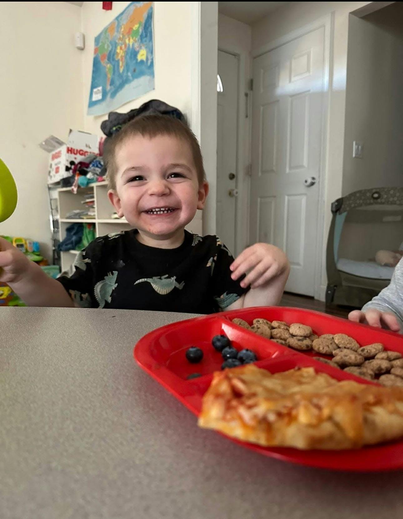 Child smiling at a table with a plate of food
