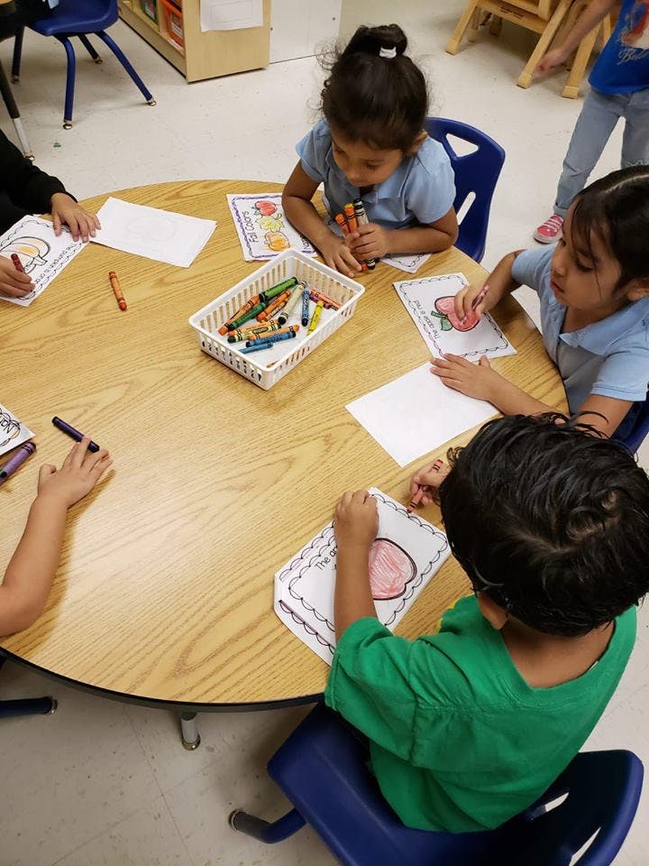 Children coloring at a round table in a classroom