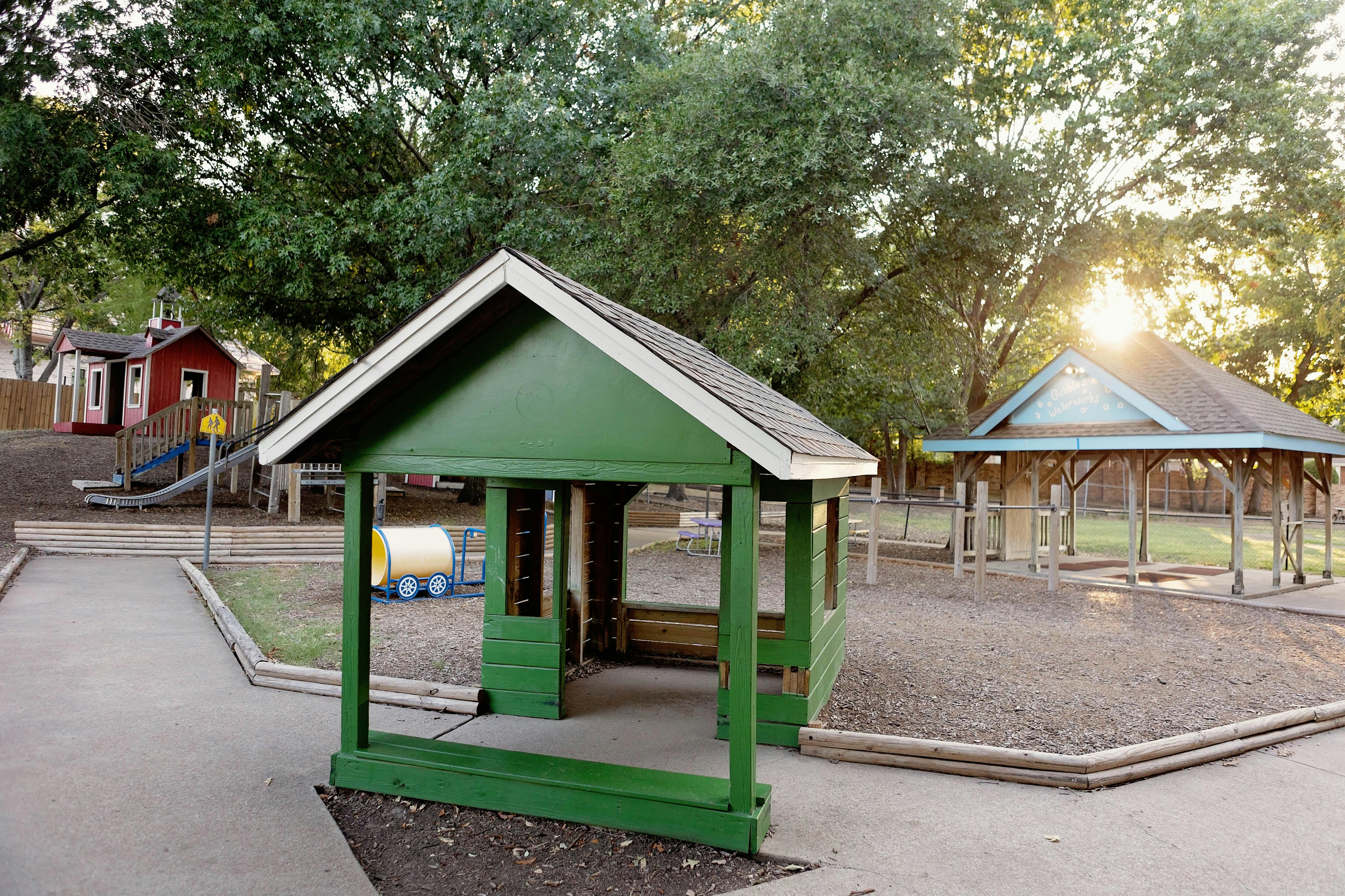 Green wooden playhouse and a gazebo on a playground