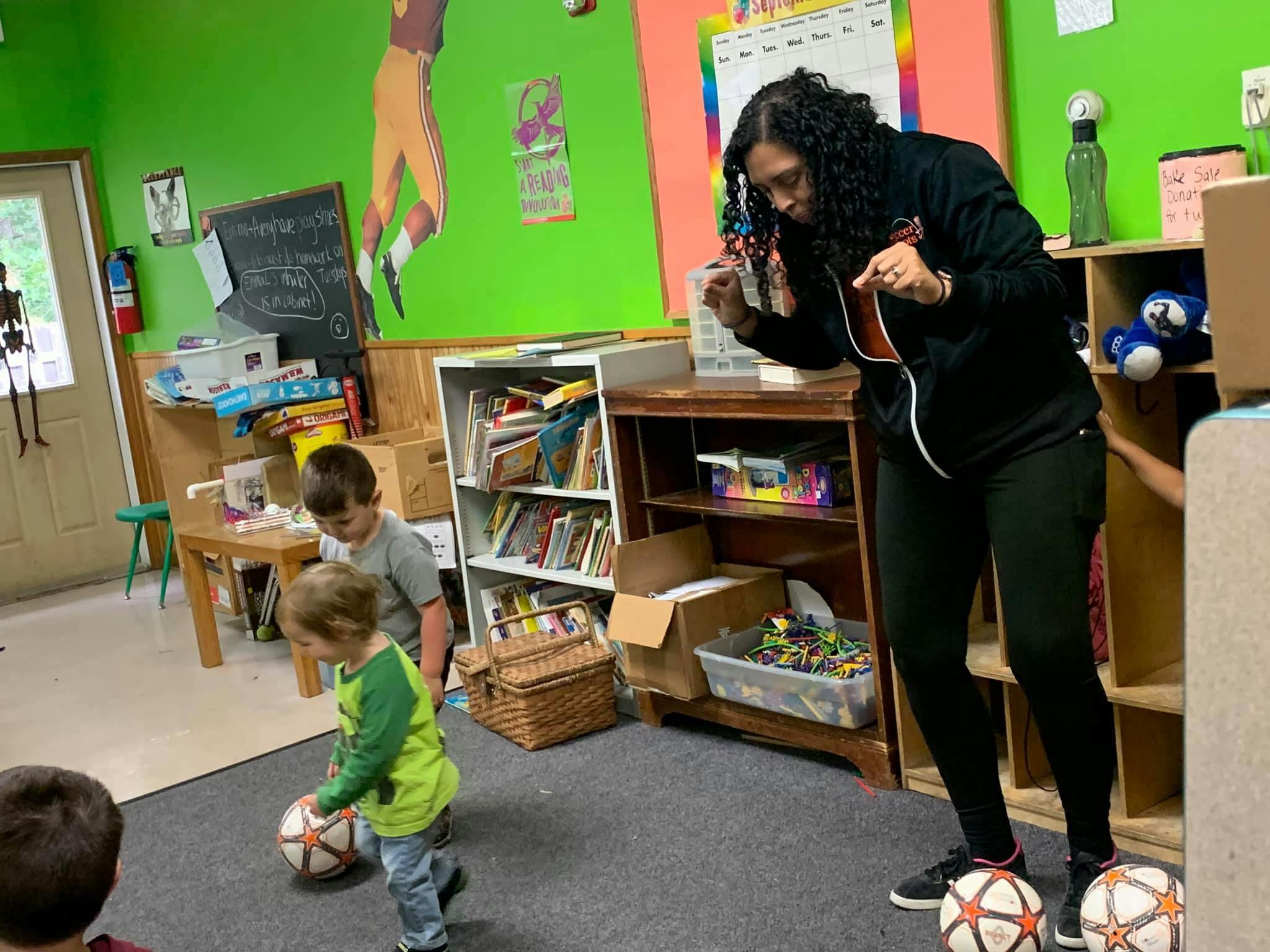 Person and children playing with soccer balls in a room