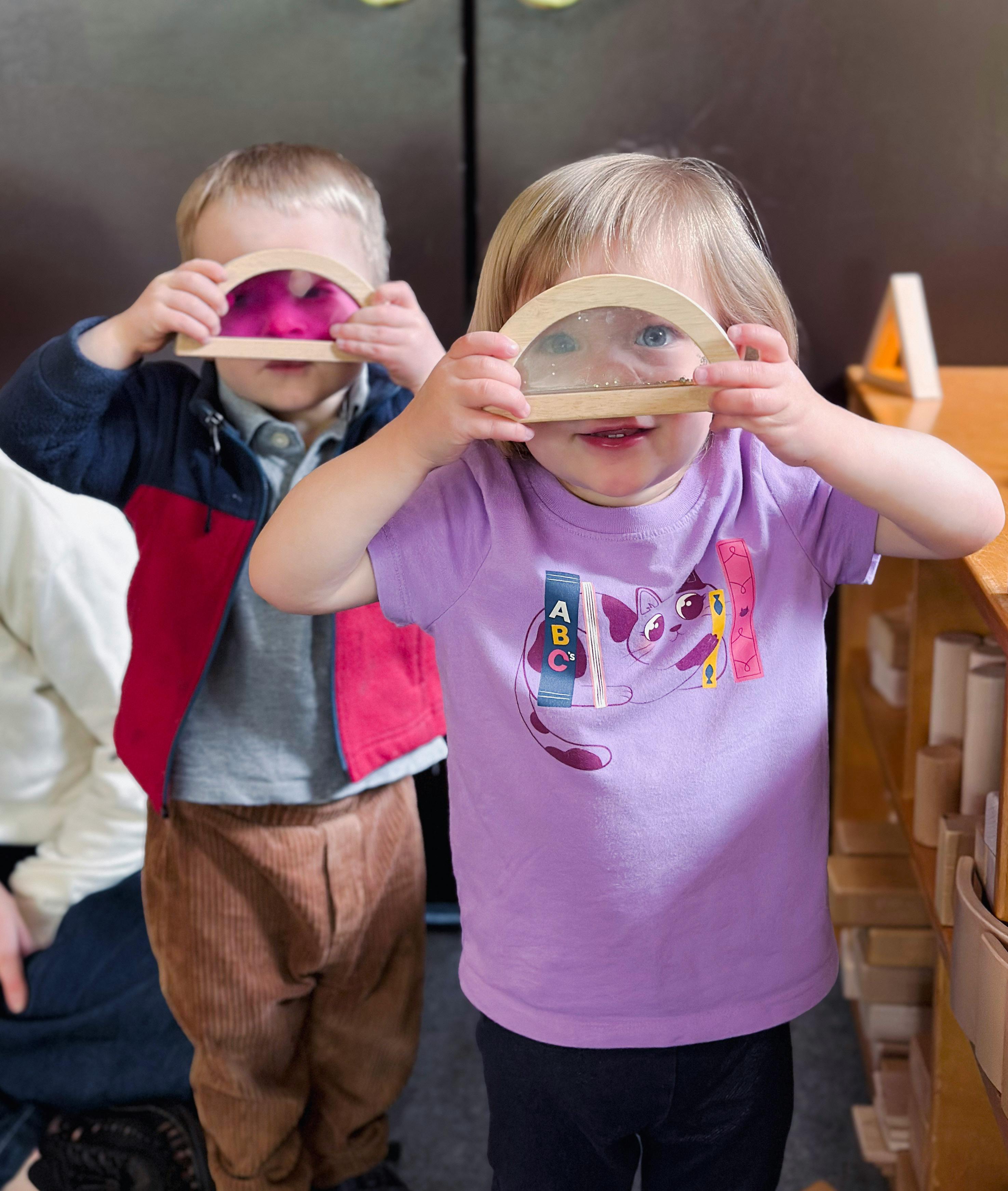 Two children holding up wooden toys to their faces