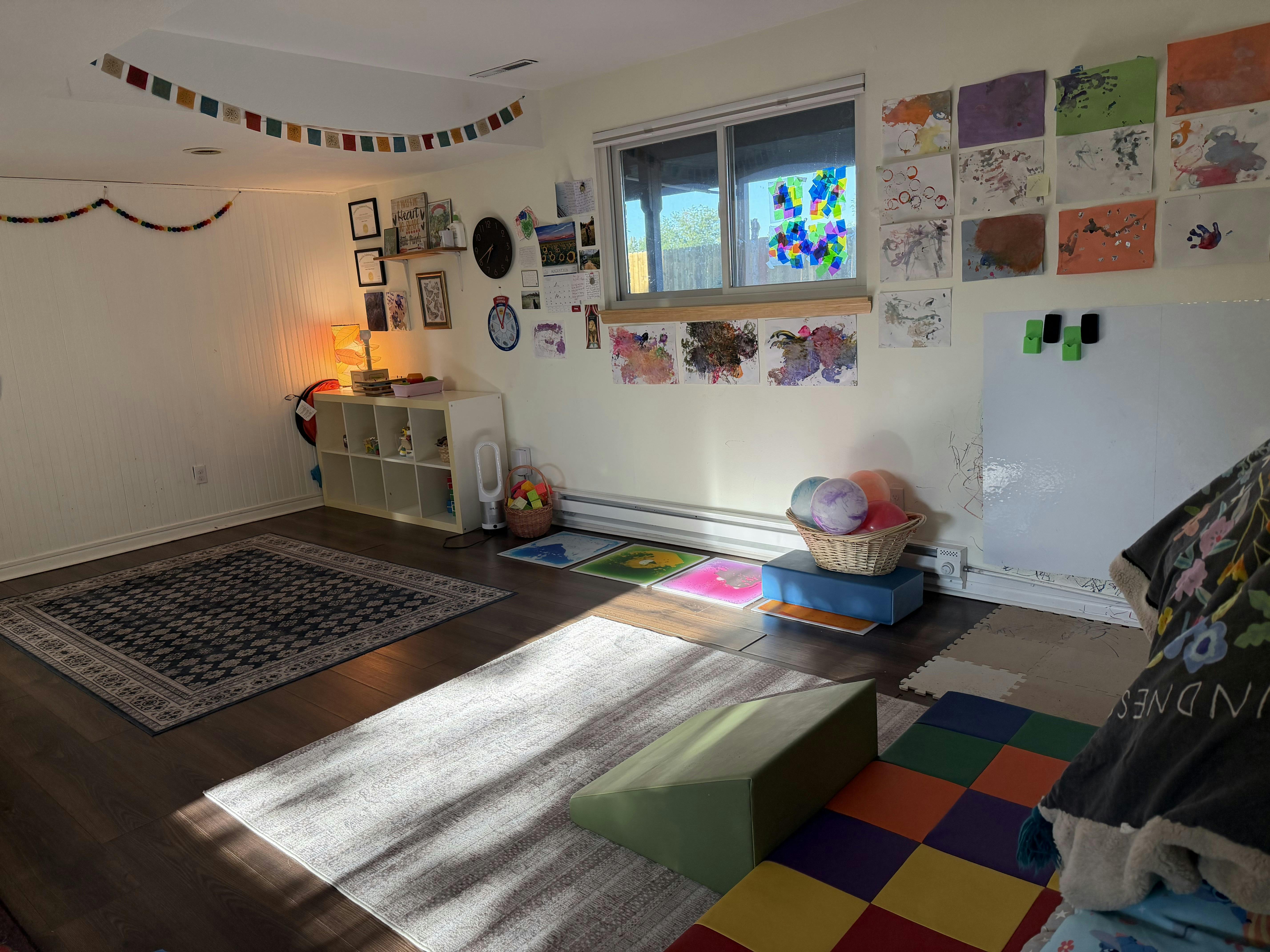 Playroom with rugs, toys, and children artwork displayed on the walls