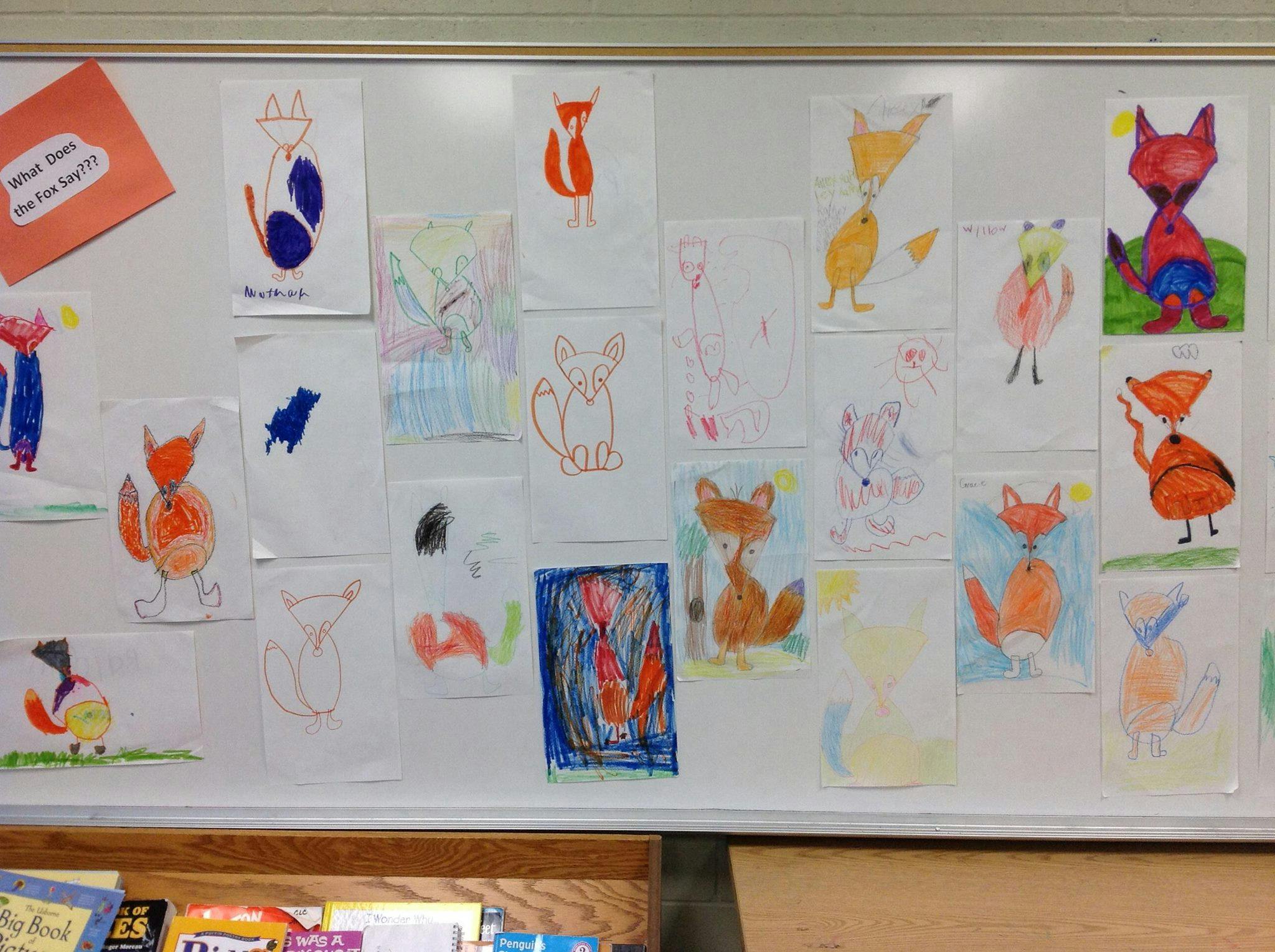 Children's drawings of foxes displayed on a white board