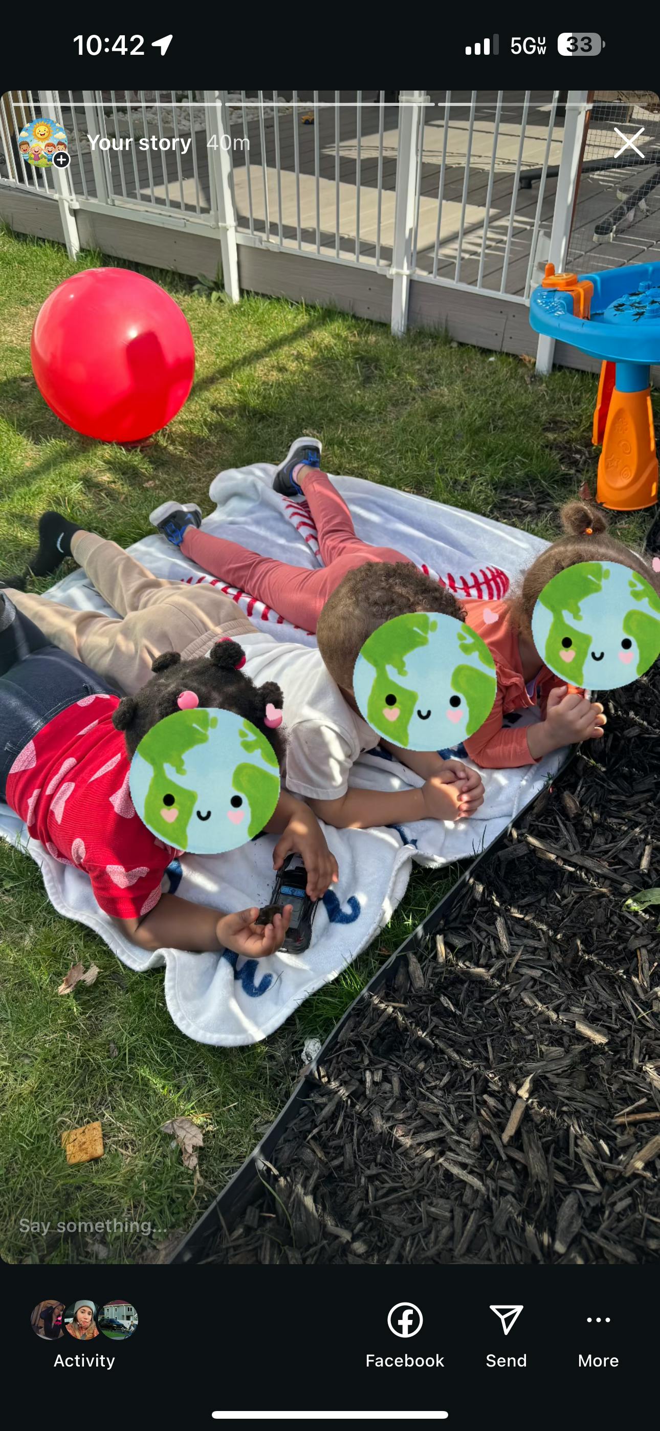 Three children lying on a blanket on grass