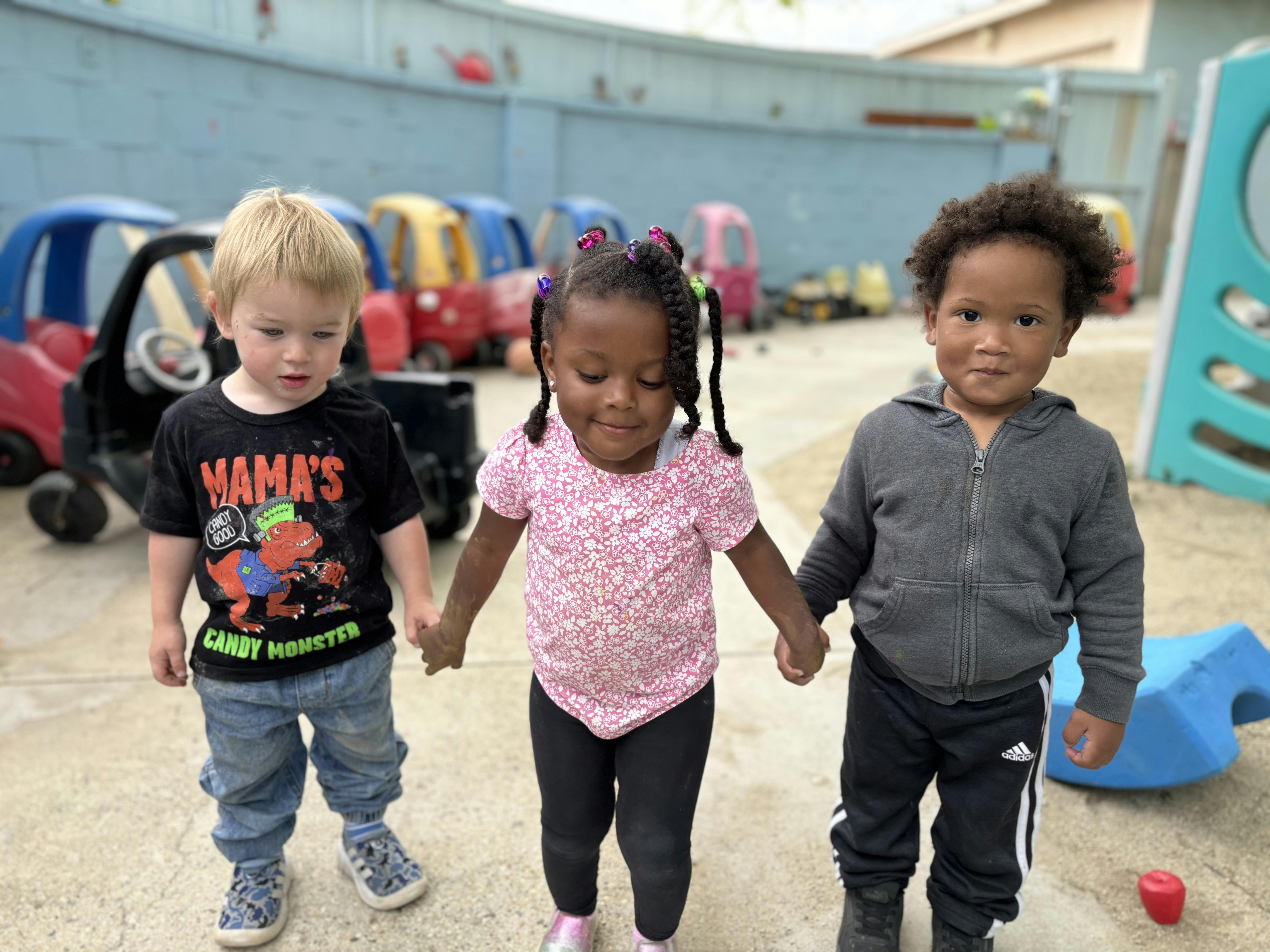 Three children holding hands on a playground