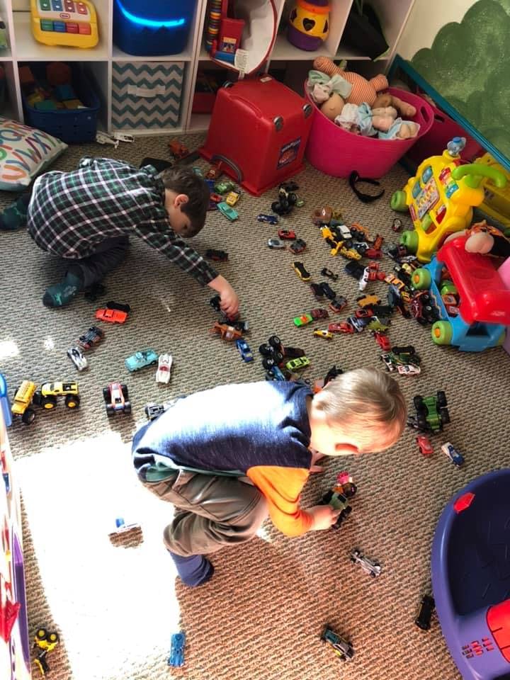 Two children playing with toy cars on a carpeted floor