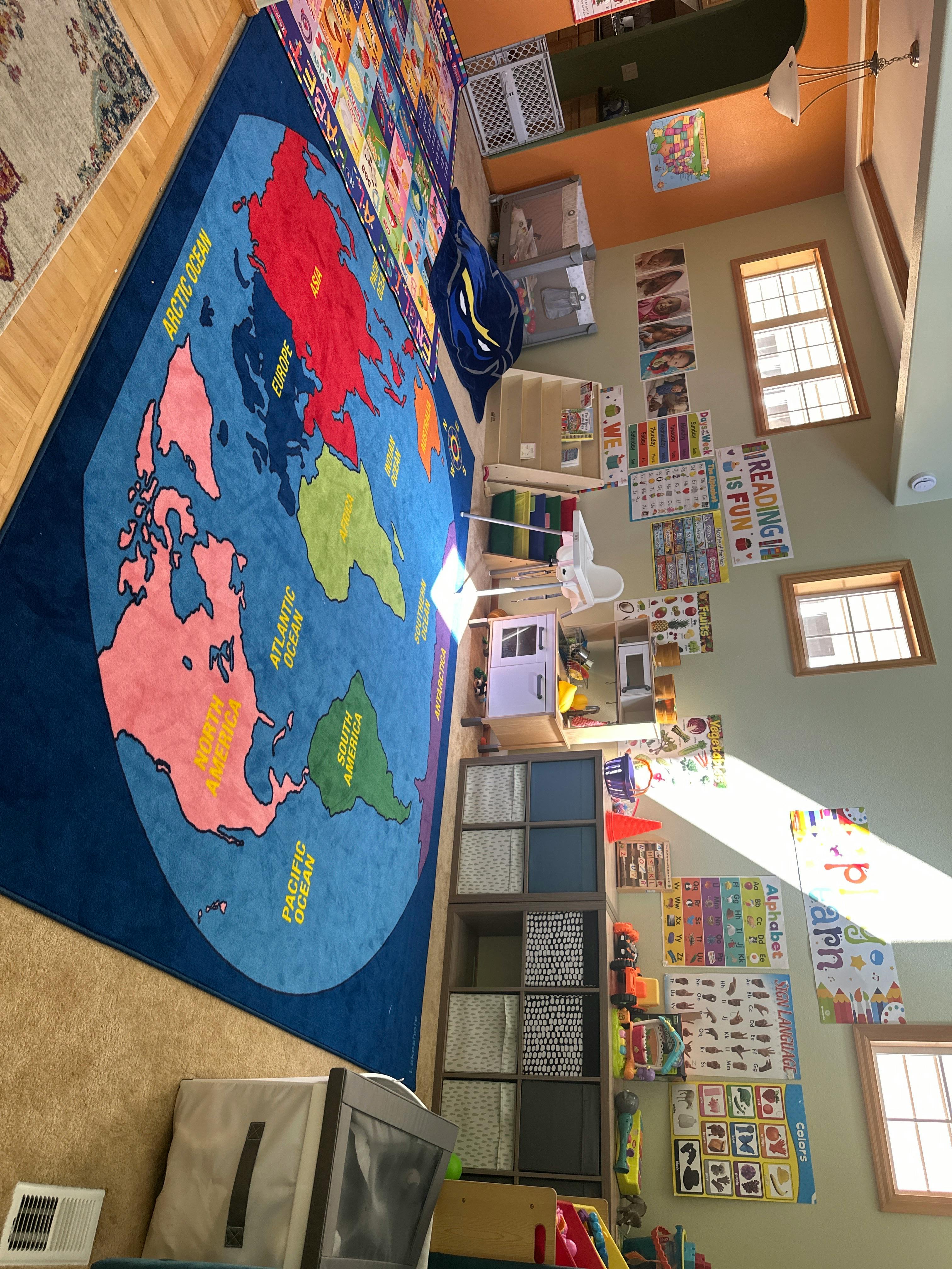 Classroom with a large world map rug and educational posters on the walls