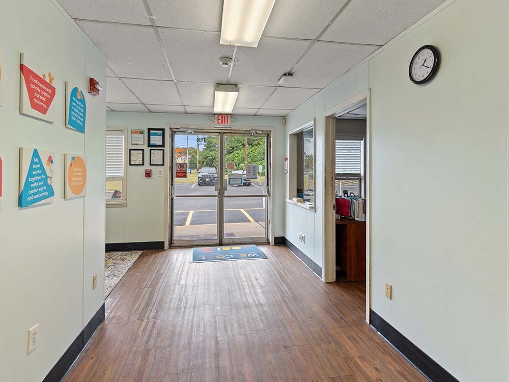 Hallway leading to glass exit doors with a clock on the wall