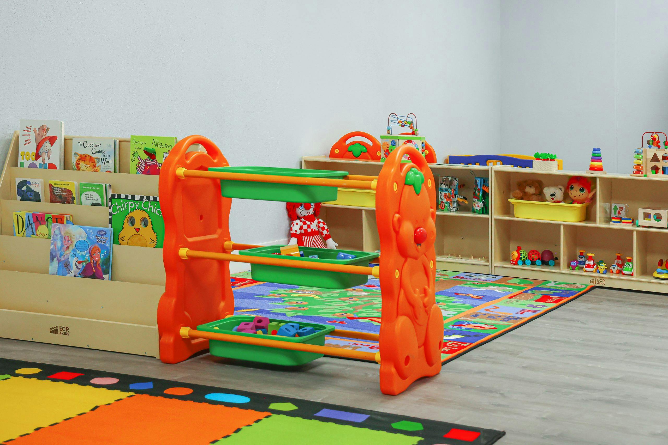 Playroom with an orange toy shelf, book display, and colorful floor mats