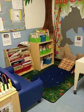 Reading nook in a classroom with a blue rug and small furniture