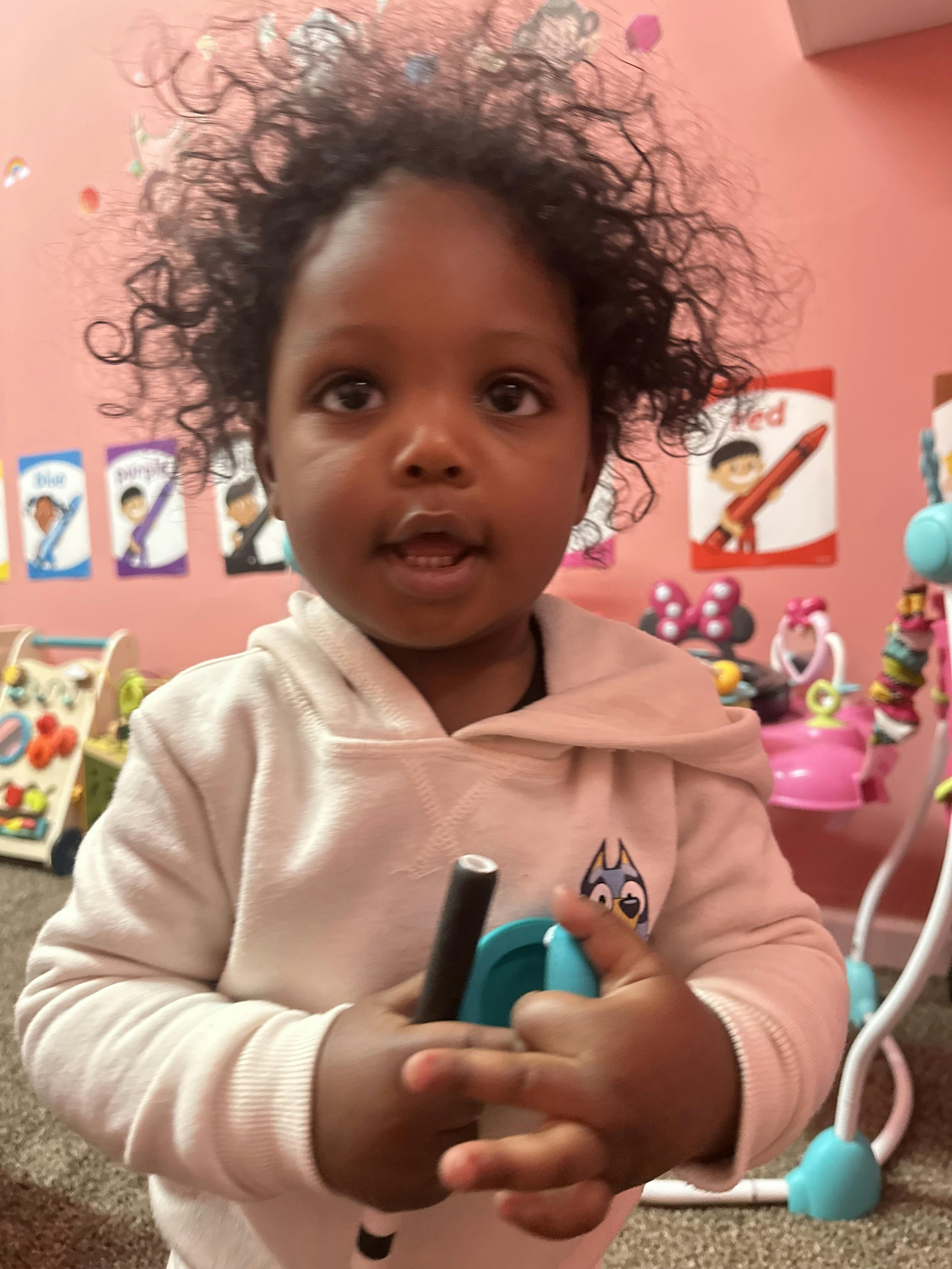 Child looking at the camera and holding a black stick