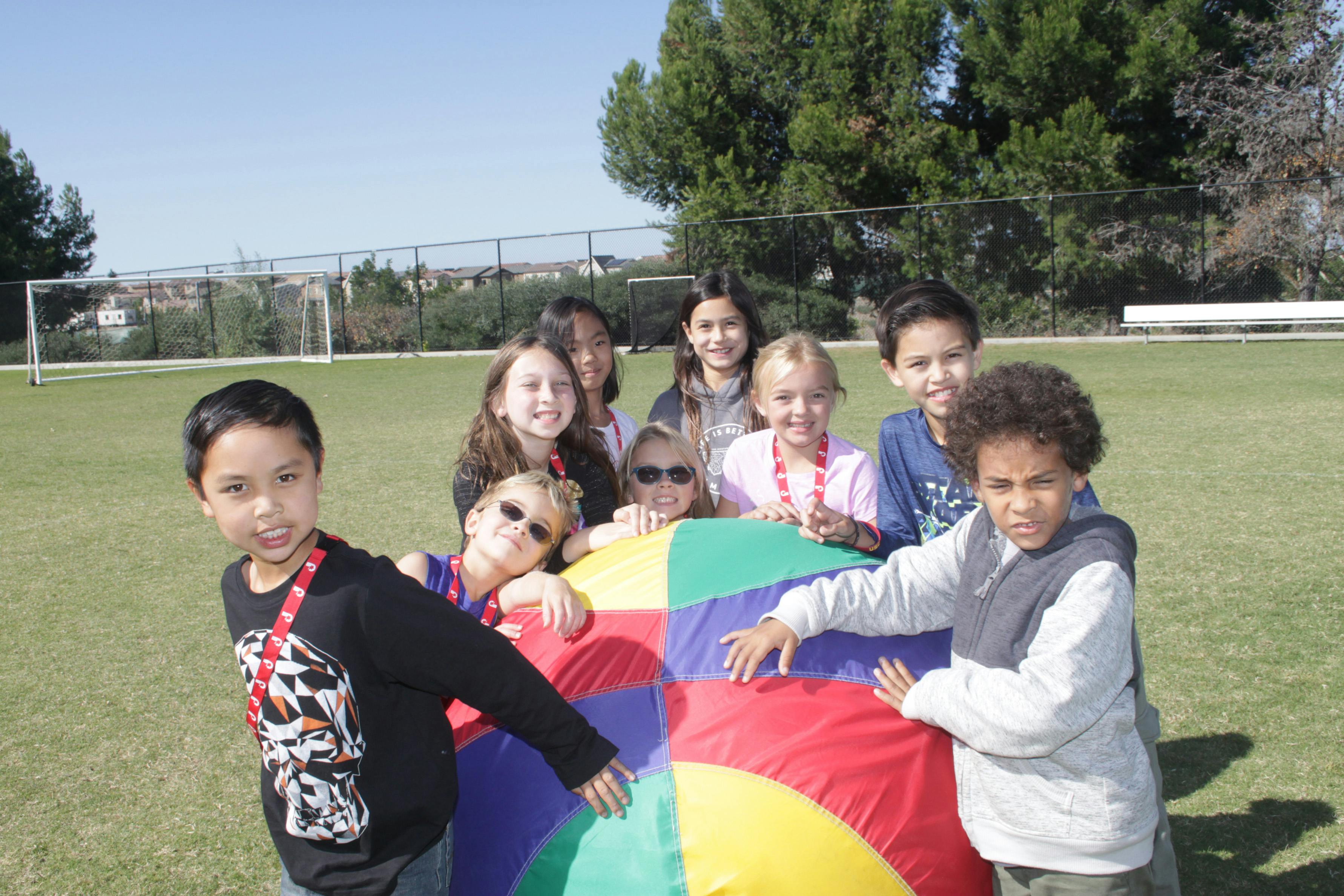 Group of children playing with a colorful parachute on a grassy field