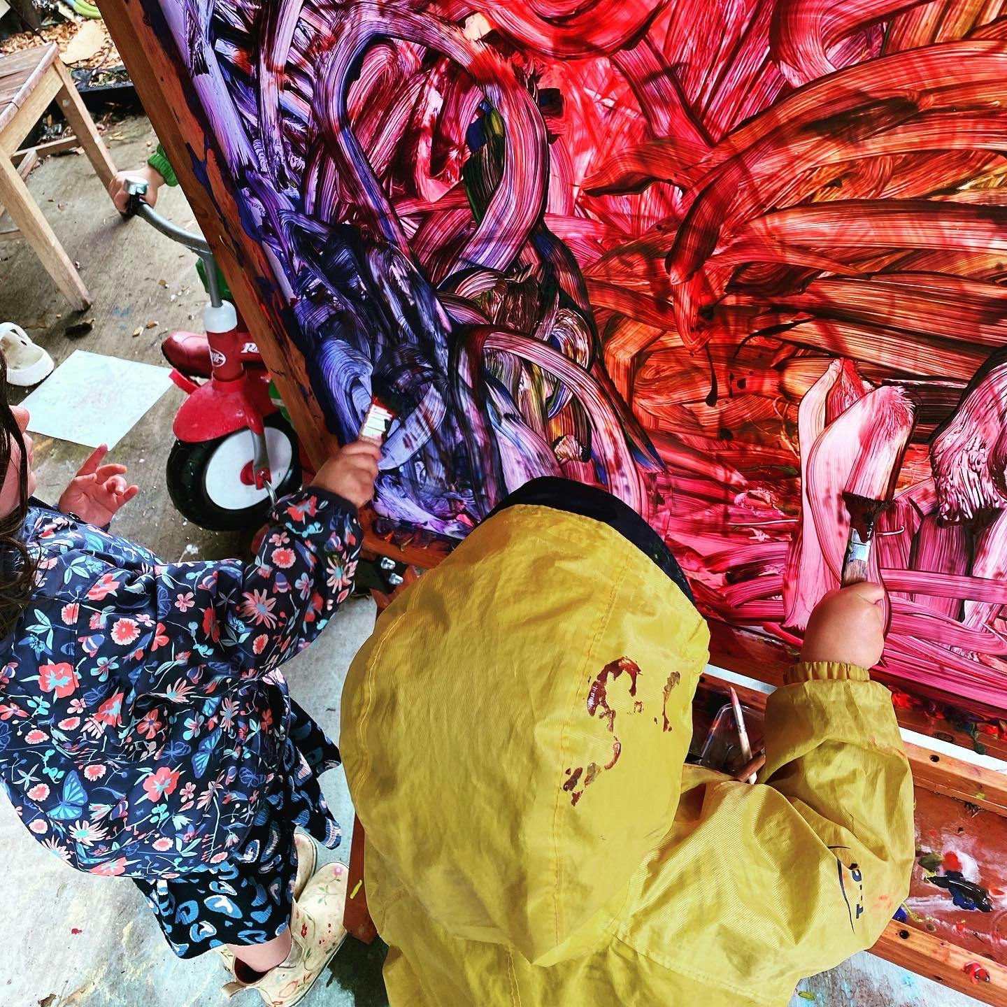 Two children painting on a large canvas