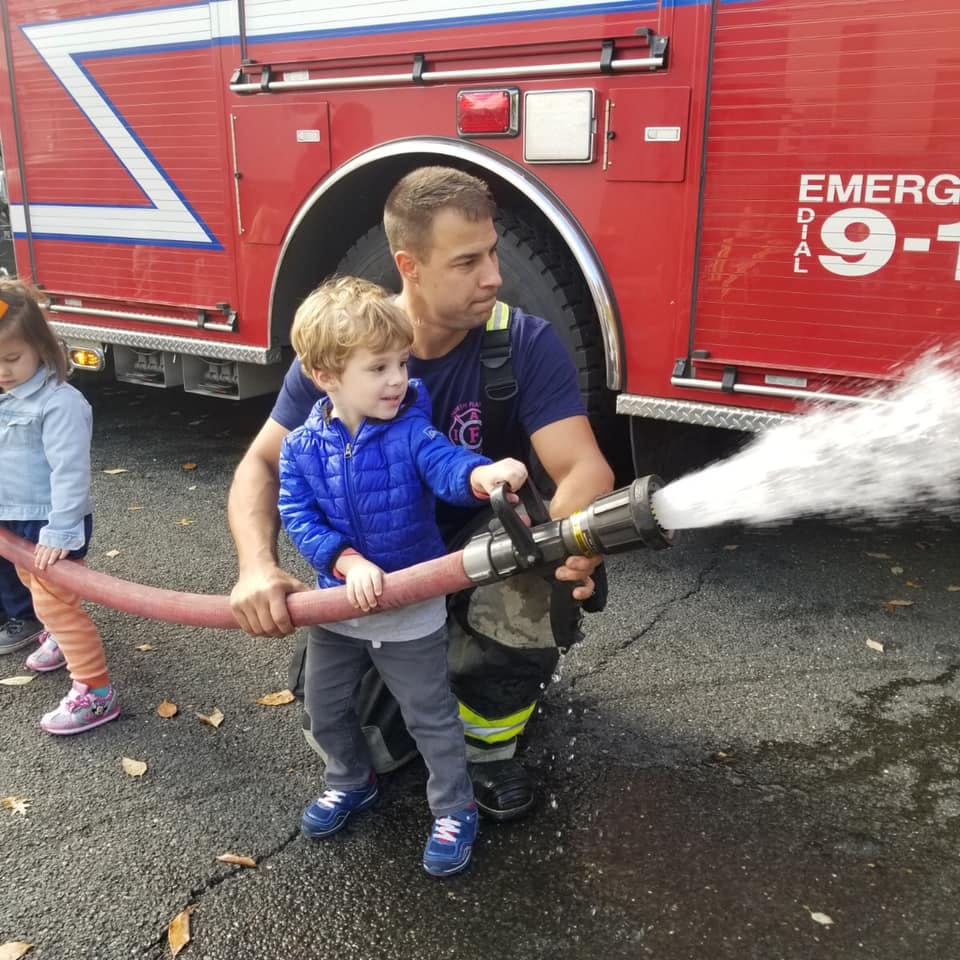 Adult and child holding a fire hose with water spraying out