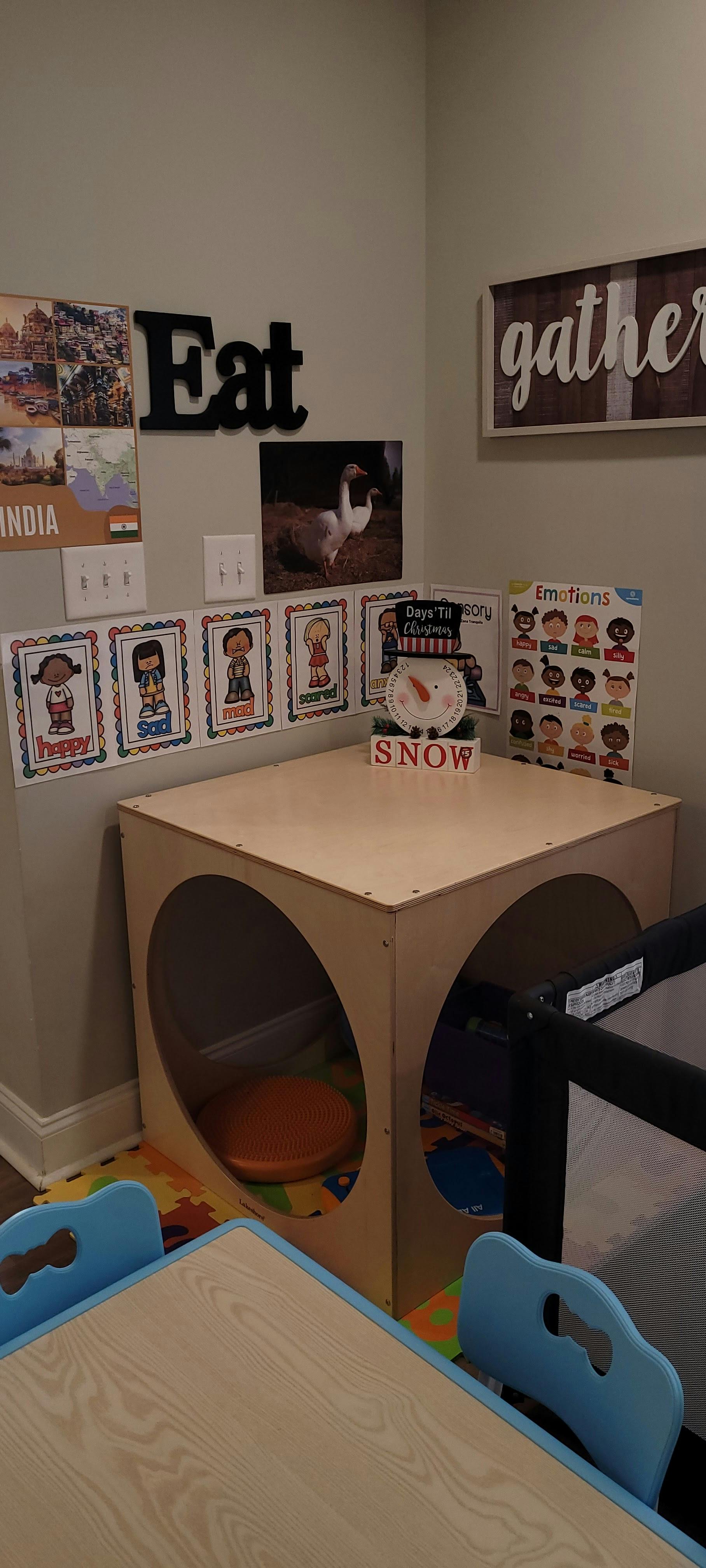Child's play area with a wooden play cube, small table, and wall decorations