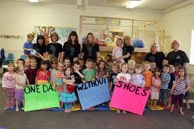 Adults and children holding signs that read "ONE DAY WITHOUT SHOES"