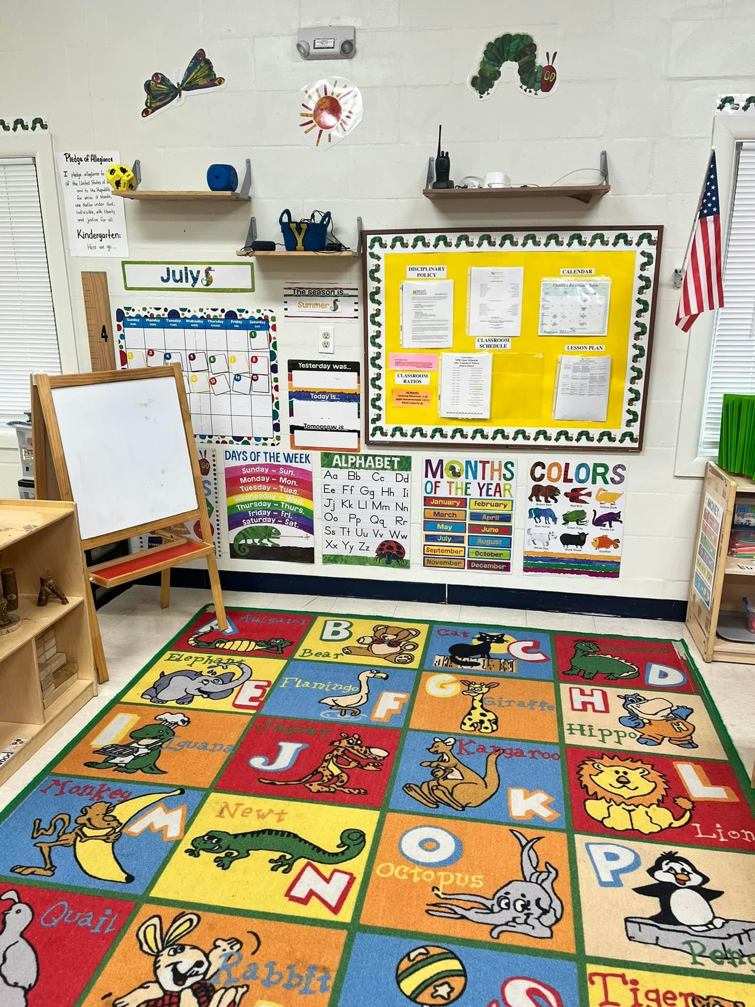 Classroom with an alphabet rug, calendar, bulletin board, and small easel