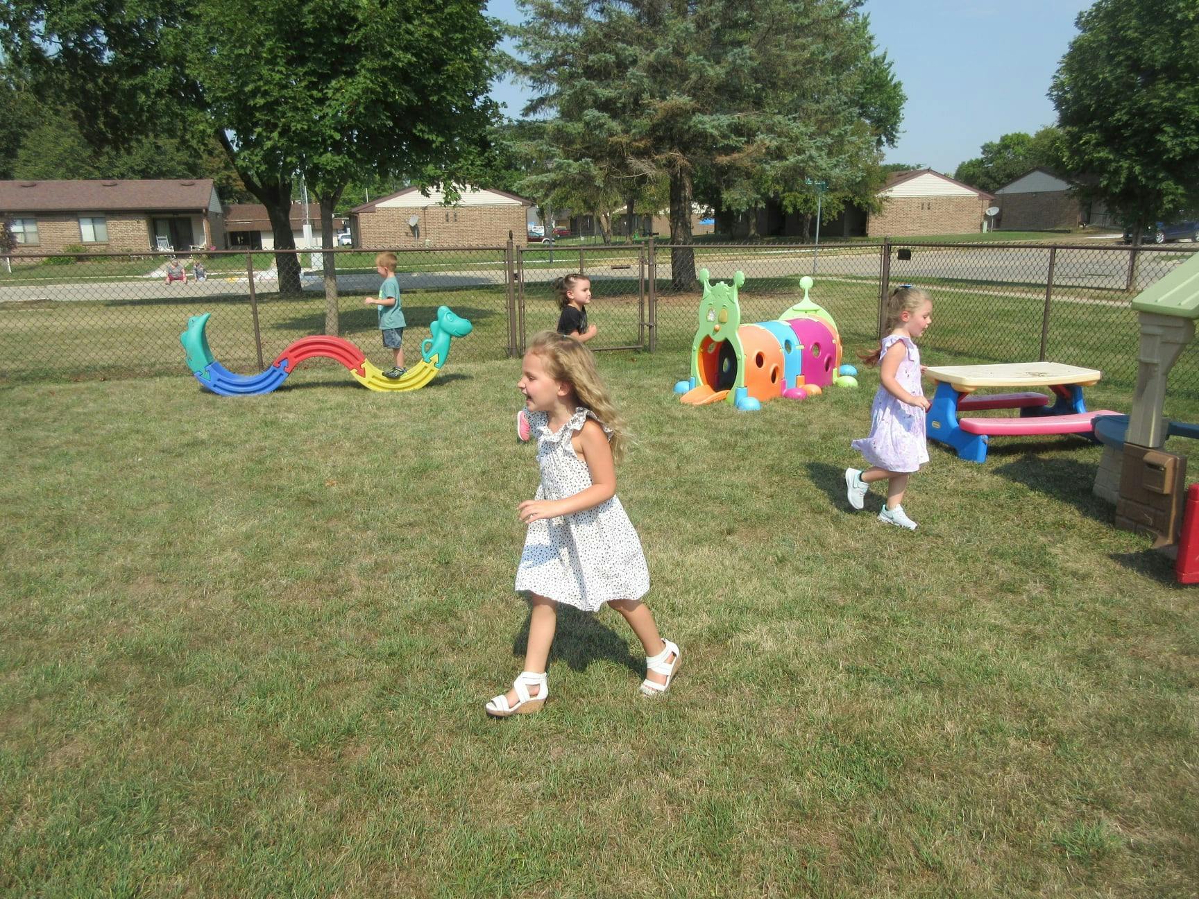Children playing on a grassy playground with colorful equipment