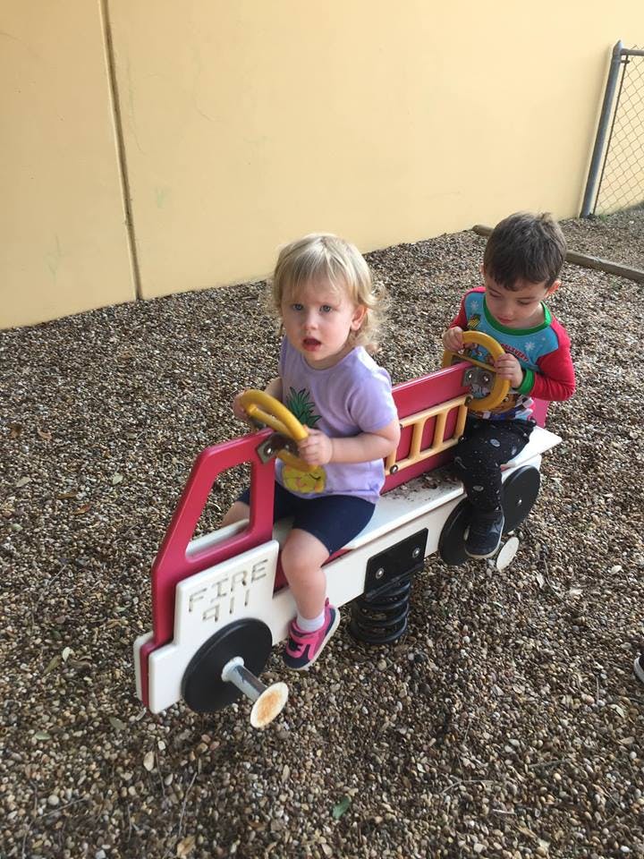 Two children on a fire truck spring rider on a playground