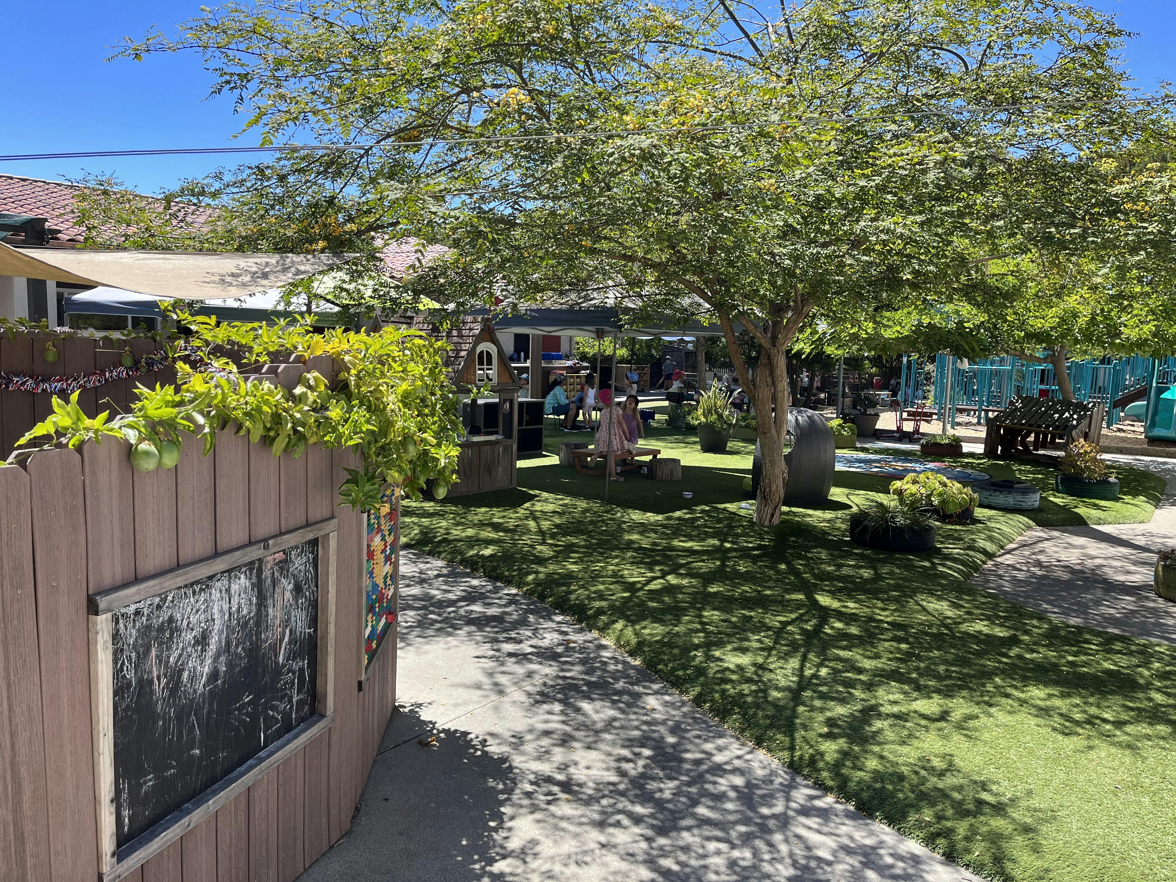 Children playing in an outdoor playground with artificial grass and shade