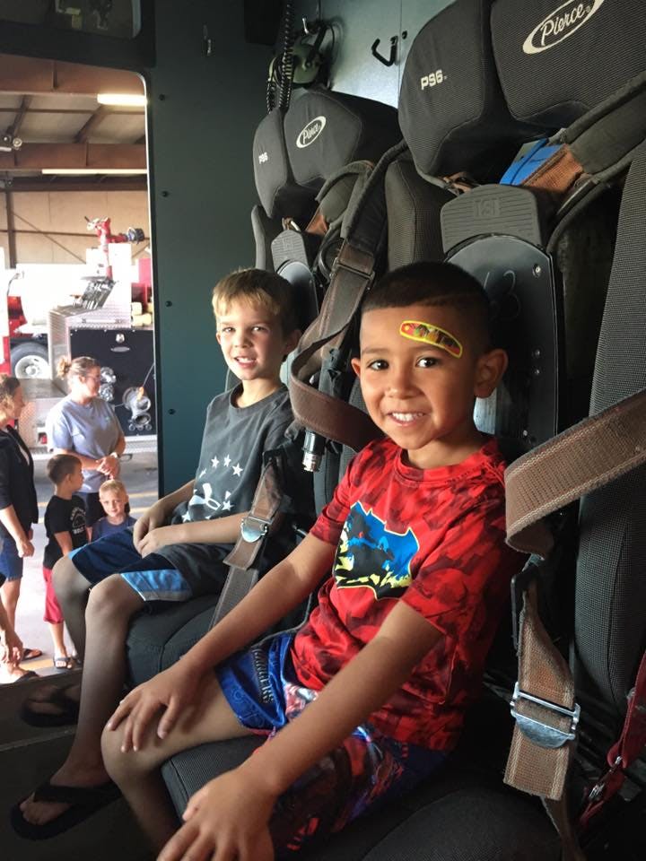 Two children sitting in large seats, one with a bandage on their forehead