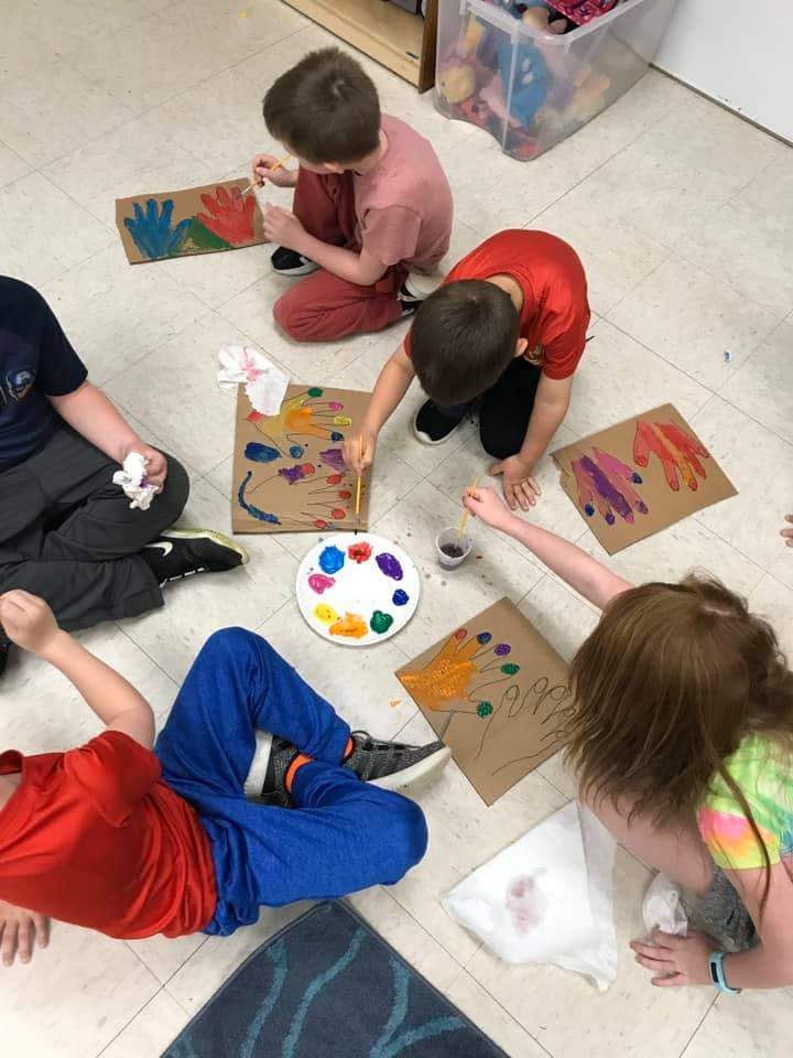 Children painting handprints on cardboard