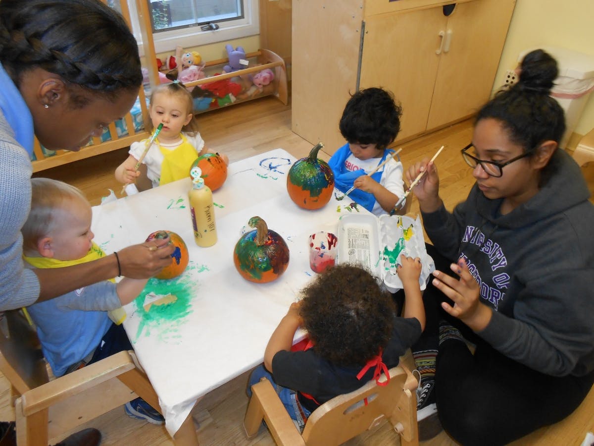 People and children painting pumpkins at a table