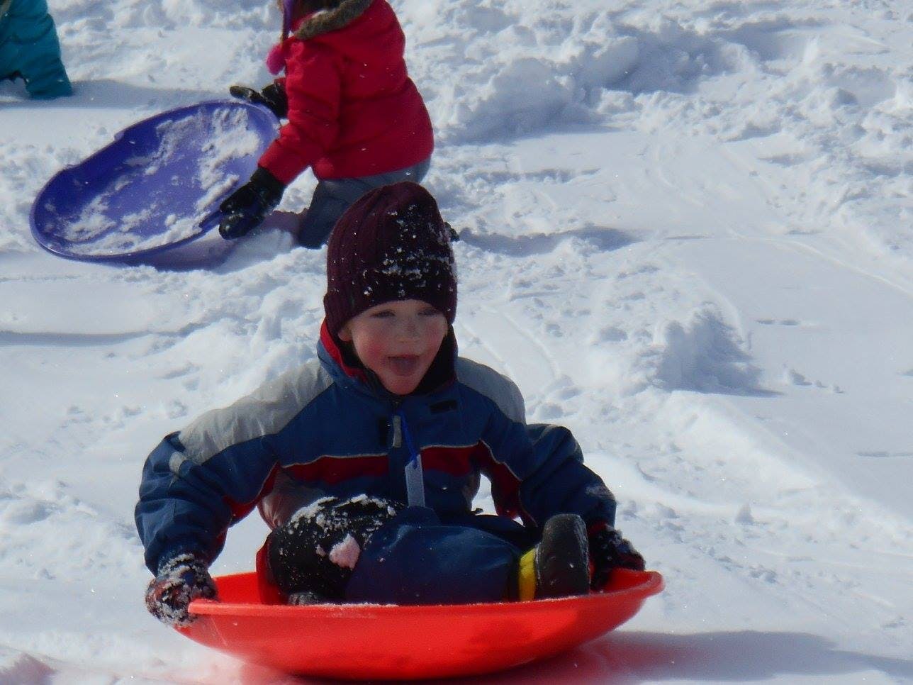 Child in a red sled on snow