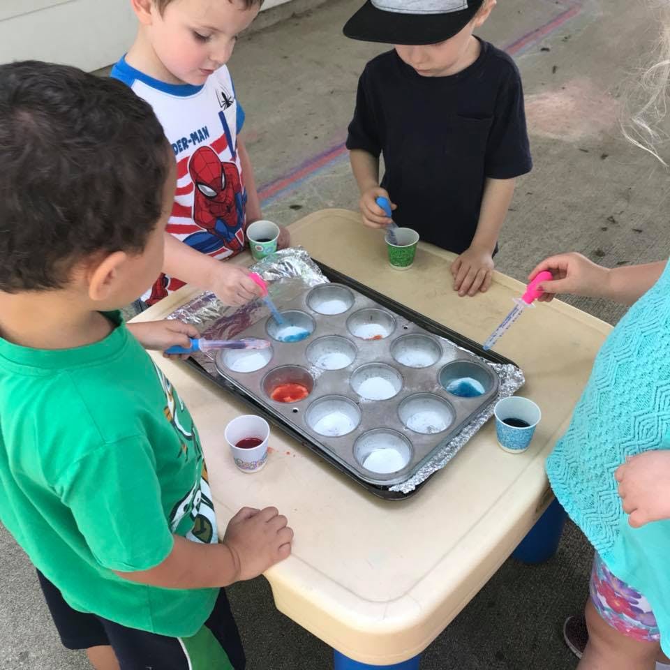 Children using droppers to add liquid to a muffin tin