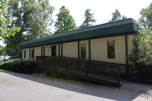 Building with a dark green roof and a wooden accessibility ramp