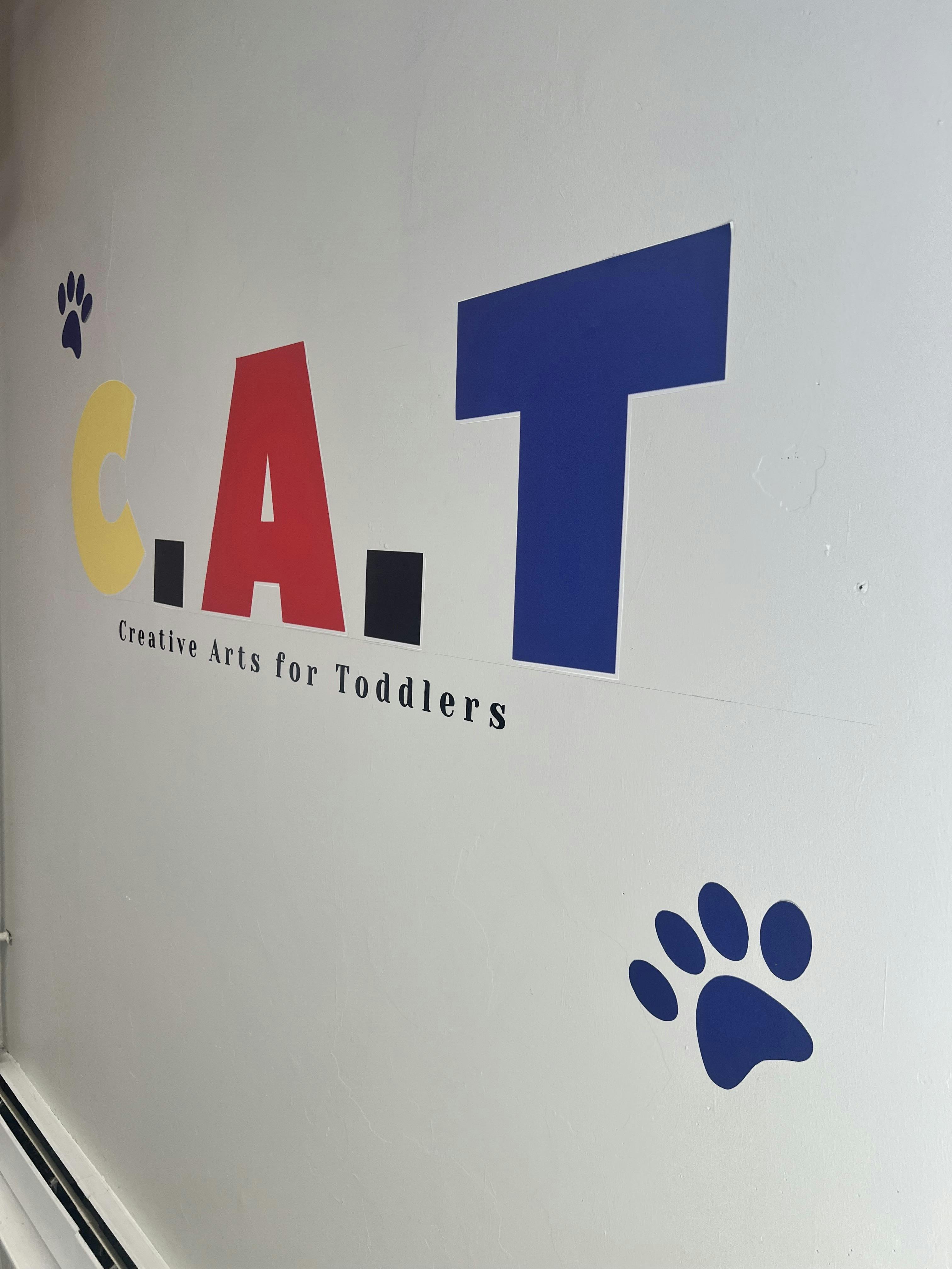 Sign on a wall that reads "C.A.T. Creative Arts for Toddlers" with paw prints