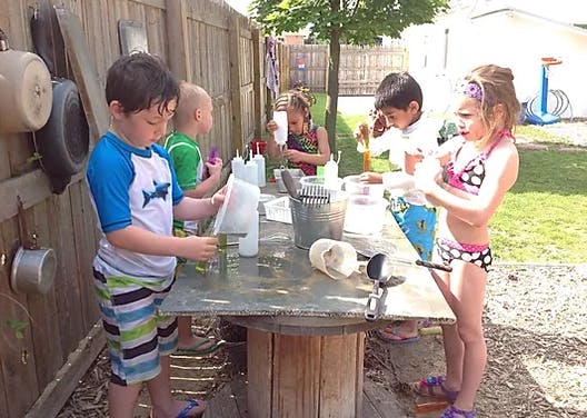 Children playing with water at an outdoor table