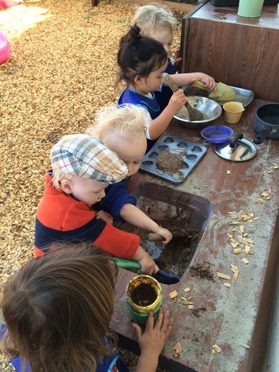Children playing with dirt and small tools at a table