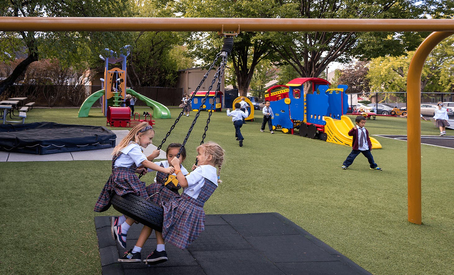 Three children on a tire swing on a playground