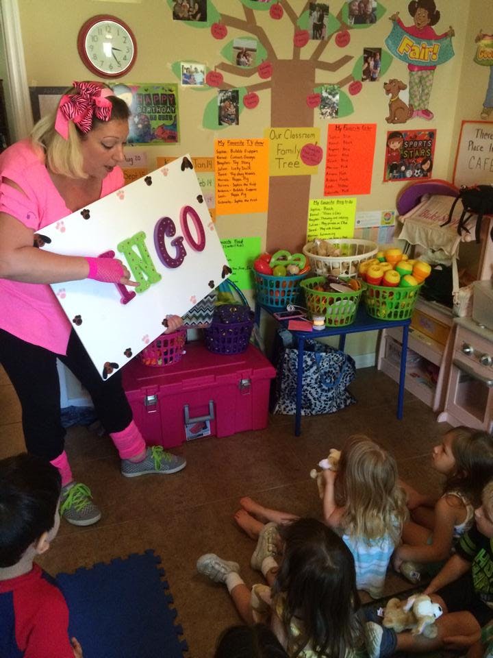 Person holding a sign that says "BINGO" to children sitting on the floor