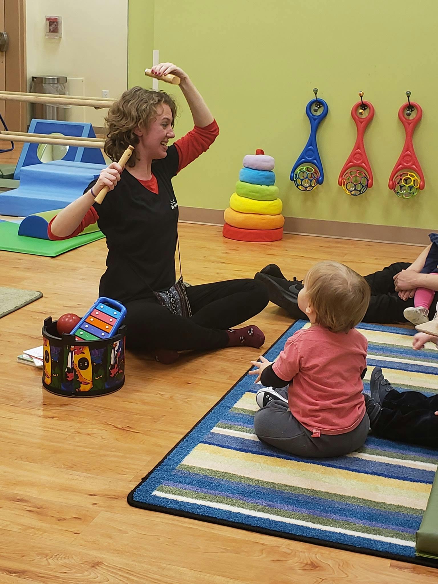 Person playing maracas for a child in a classroom