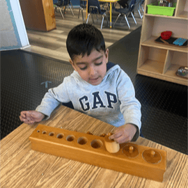 Child playing with a wooden cylinder block set