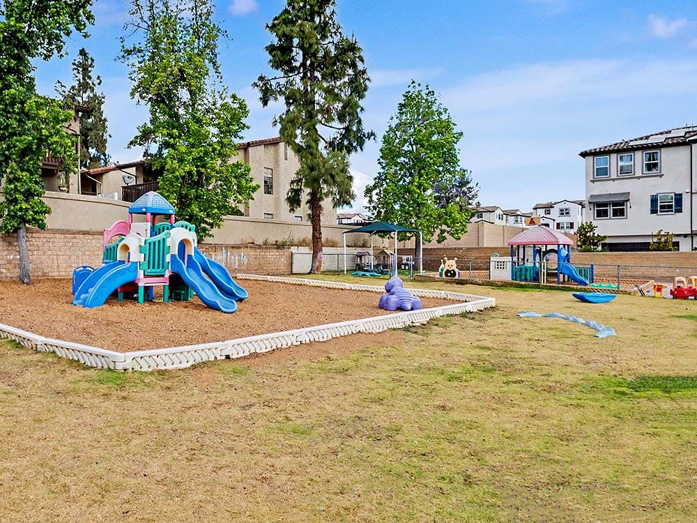 Colorful playground equipment on wood chips and grassy area
