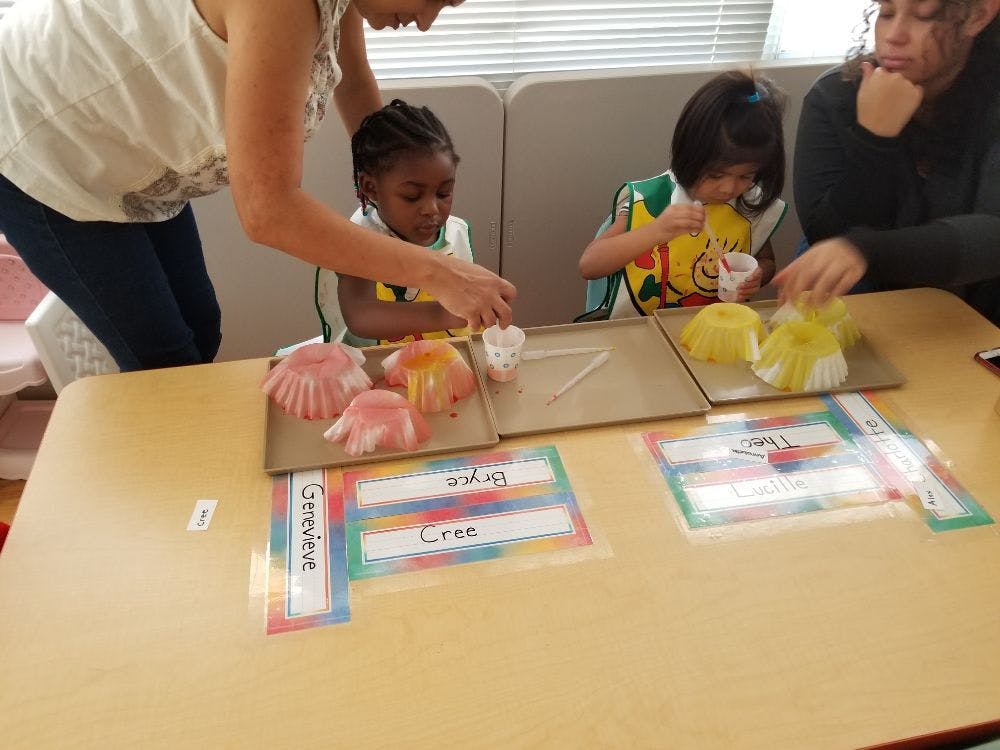 Adults and children at a table doing an activity with craft supplies