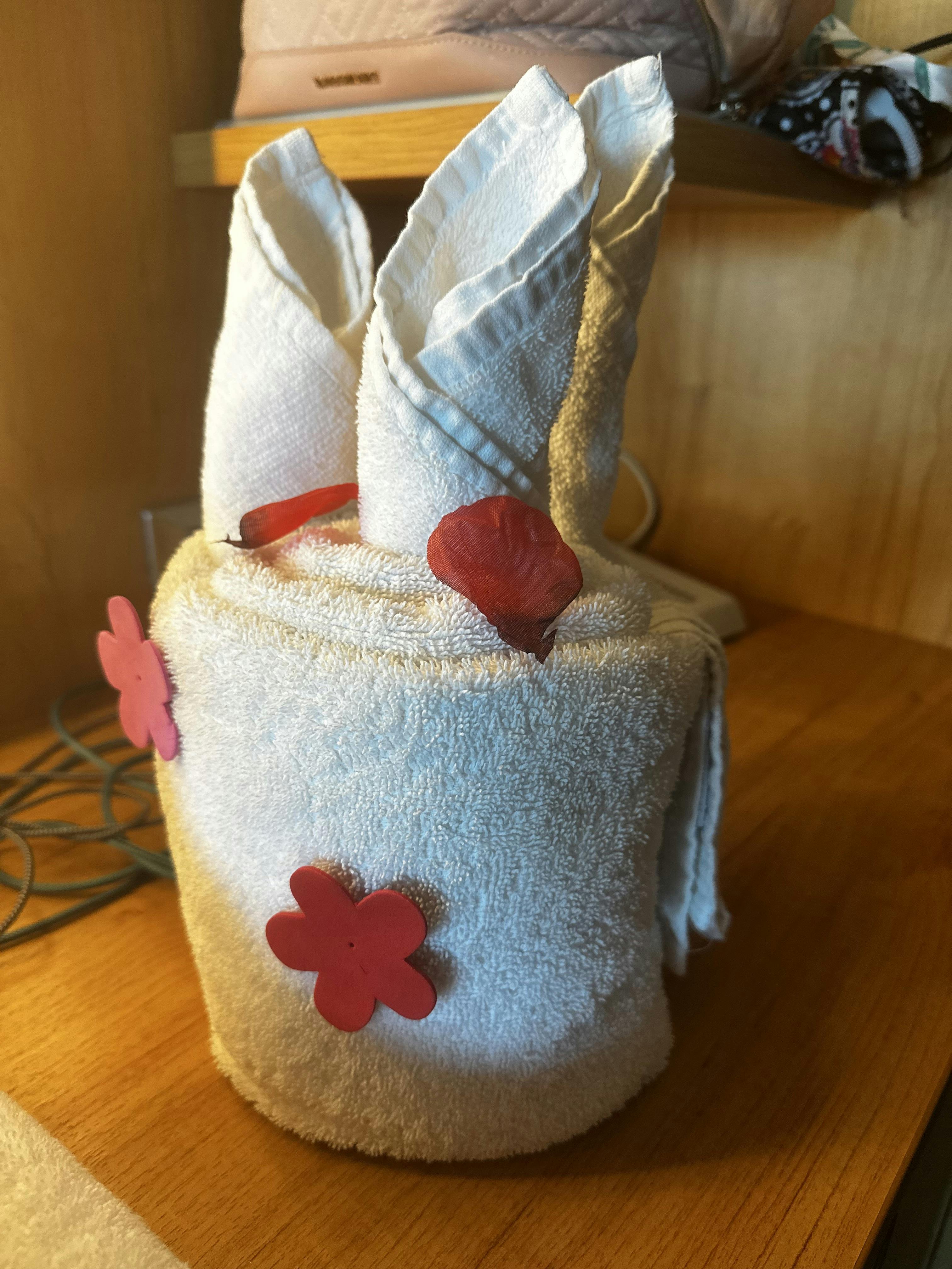 White towel folded into a bunny shape with red flower decorations
