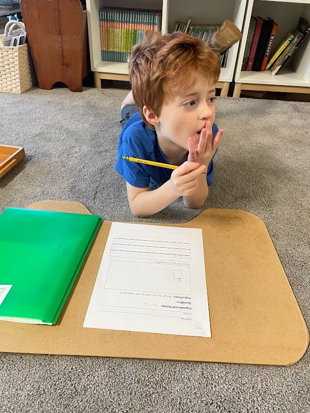 Child lying on floor with pencil and paper